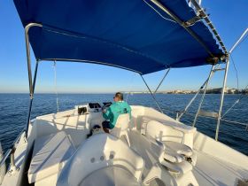 A view of the helm area inside a boat, featuring a captain at the controls, showcasing the spacious seating and modern design ideal for comfortable cruising.