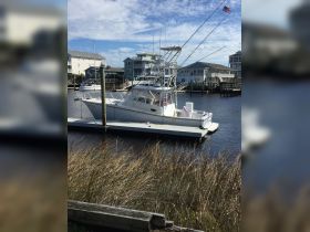 A fishing boat docked at the marina, surrounded by scenic waterfront homes, perfect for fishing trips and coastal adventures.