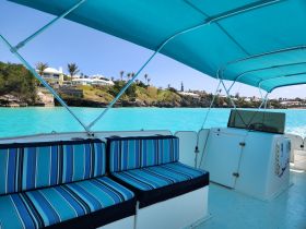 A cozy interior view of a boat featuring striped seating and a helm, perfect for enjoying the turquoise waters and scenic surroundings.