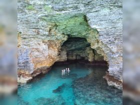 Two swimmers enjoy the crystal-clear waters inside a stunning cave, showcasing a perfect adventure spot for exploration and relaxation.