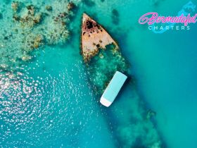 Aerial view of a boat near a shipwreck in crystal-clear waters, showcasing the stunning marine environment — perfect for adventure seekers exploring the underwater world.
