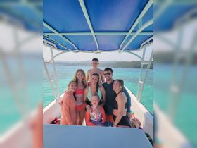 A joyful group of family and friends poses together on a boat, surrounded by stunning turquoise waters — perfect for memorable adventures and celebrations on the water.