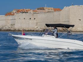A couple enjoys a scenic boat ride, with historic architecture in the background — perfect for exploring coastal destinations.
