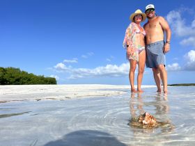 A couple enjoys a sunny day at a sandbar, capturing a memorable moment with the beautiful beach backdrop — perfect for romantic getaways or beach celebrations.