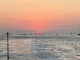 A breathtaking sunset over a harbor filled with boats, creating a picturesque scene perfect for evening cruises and relaxation on the water.