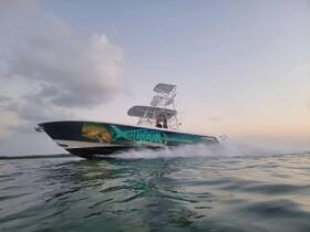 A dynamic shot of a speedboat named 'Off the Hook' cruising through calm waters, showcasing its vibrant design and sleek profile.