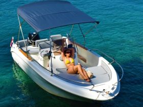 A woman relaxes on the deck of a boat, soaking up the sun in a vibrant bikini against a stunning turquoise backdrop — perfect for summer getaways and water adventures.