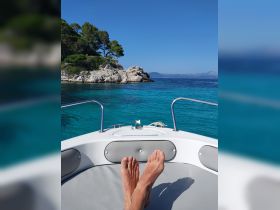 A relaxing view from the bow of a boat, showcasing beautiful turquoise waters and rocky shores, perfect for a day of leisure on the water.