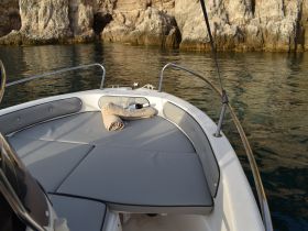 A cozy lounge area on a boat, featuring comfortable seating and a towel, perfect for relaxing while enjoying the serene waters.