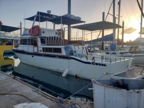 A beautiful yacht docked in the marina, showcasing its structure and design against a serene sunset backdrop.