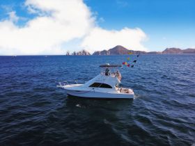 A stunning aerial view of a yacht cruising through clear blue waters, with picturesque mountains in the background — perfect for showcasing boating adventures.