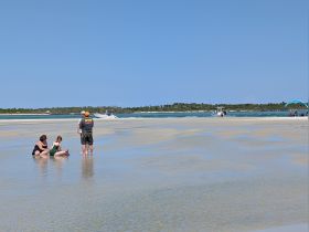 A family enjoys a sandbar stop, playing in the shallow water and soaking up the sun — a perfect day at the beach.