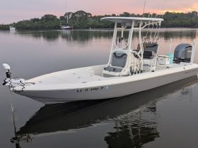 A sleek center console boat docked in calm waters, showcasing its modern design and fishing gear, perfect for a day on the water.