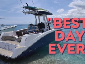 A sleek speedboat docked in clear waters, showcasing its stylish design and equipped with fishing rods and a paddleboard — perfect for a day of adventure on the water.