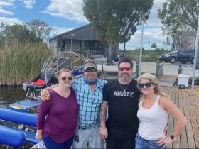 A cheerful group poses together by an airboat, capturing a memorable moment before their adventure — perfect for friends and family outings.