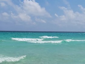 A scenic view of turquoise waters and gentle waves, capturing the essence of a serene beach environment.