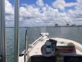 A view from the helm of a boat, showcasing the console and surrounding water under a partly cloudy sky — perfect for a day of boating adventures.