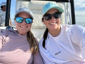 Two friends enjoy a sunny day on the water, smiling for a selfie on a boat — perfect for capturing memorable moments during a boating adventure.