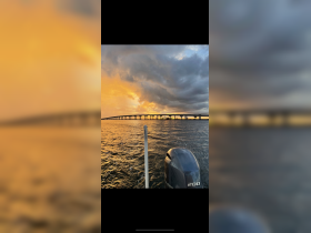 A stunning sunset view over the water with a bridge in the background, capturing the serene beauty of a boating experience.