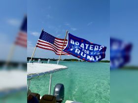 A vibrant display of American and political flags on a boat cruising through clear turquoise waters, showcasing a spirited boating experience.
