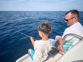 A father and son enjoy a fishing trip together on the open ocean, creating lasting memories in a beautiful marine setting.