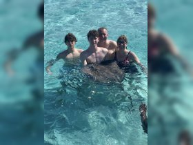 A group of four enjoys a memorable experience swimming with stingrays in crystal-clear waters, showcasing the thrill of wildlife encounters in a tropical paradise.