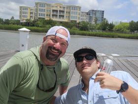 Two friends enjoy a sunny day on the dock, sharing laughs and drinks — a perfect moment for relaxation and camaraderie by the water.