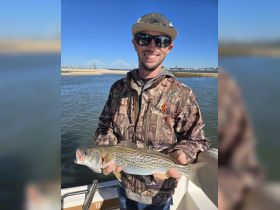 A happy angler proudly displays his catch while enjoying a day of fishing on the water, showcasing the thrill of outdoor adventures.