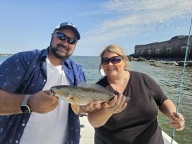A couple proudly displays their catch while fishing on a boat, showcasing a fun day on the water.