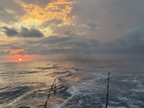 A stunning sunset over the ocean, captured from a fishing boat, showcasing the tranquil beauty of the sea during twilight.