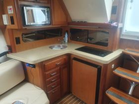 Interior view of a boat's kitchen area, featuring a microwave, sink, and storage cabinets — perfect for meal preparation while on the water.