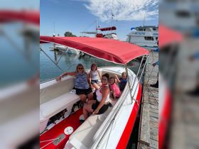 A joyful group of family members relaxes on a boat at the dock, ready for a day of fun on the water.