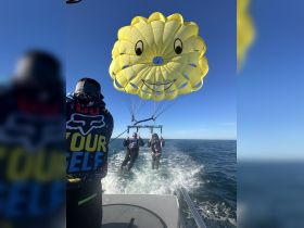 A thrilling parasailing experience with a couple soaring above the water, enjoying the stunning views and adventure on a sunny day.