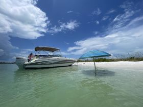 A sleek speedboat docked in shallow waters, complemented by a colorful beach umbrella, perfect for a relaxing day on the water.