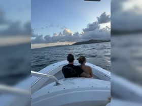A couple enjoys a romantic moment on a boat, embracing as they take in the stunning sunset views — perfect for intimate getaways on the water.