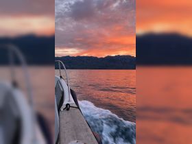 A stunning sunset view from the side of a boat, showcasing vibrant colors reflecting on the water — perfect for serene evening cruises.