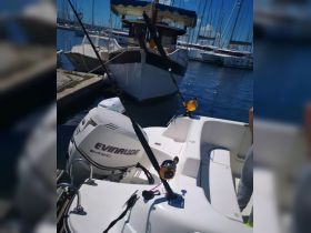 A view of the interior of a fishing boat, featuring the helm and fishing gear, perfect for a day out on the water.