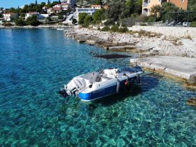 A small boat is docked in crystal-clear waters, showcasing the serene coastal landscape — perfect for fishing or leisure activities.
