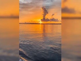 A stunning sunset reflects on calm waters, creating a picturesque scene perfect for evening boat cruises.