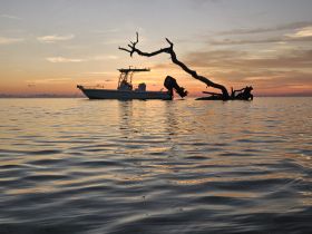A serene sunset view featuring a boat silhouetted against the colorful sky, creating a picturesque scene perfect for tranquil boating experiences.