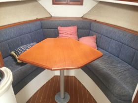 Cozy interior seating area of a boat featuring a wooden table and comfortable cushions, perfect for dining or relaxing while on the water.