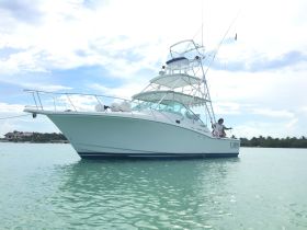 A Cabo Express fishing boat is anchored in clear waters, with crew members preparing for a day of fishing — an ideal setting for ocean adventures.