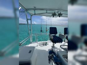 A view of the helm and seating area on a fishing boat, showcasing the fishing rods and clear turquoise waters — perfect for a day of deep-sea fishing.