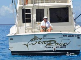 A fisherman relaxes on the deck of the 'Sea Rose' boat in the clear waters of Cozumel, Mexico, showcasing a perfect day for fishing adventures.