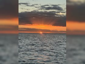 A stunning sunset over the ocean, with vibrant colors reflecting on the water — a perfect backdrop for evening boat cruises.