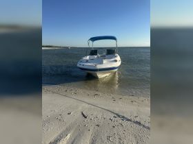 A speedboat rests on the sandy shore, showcasing its sleek design against a clear blue sky — perfect for a day of fun on the water.