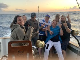 A lively group enjoys a fishing trip at sunset, capturing the joy of camaraderie on the open water.