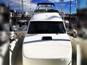 A close-up view of a yacht's front at the dock, showcasing its sleek design and structure, with a person visible in the background.