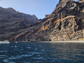 A stunning view of rocky cliffs along the coastline, with boats anchored in the serene waters — perfect for exploring the natural beauty of the area.