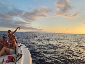 A group of friends enjoys a beautiful sunset on the water, celebrating with drinks aboard a boat — a perfect moment for unforgettable memories.